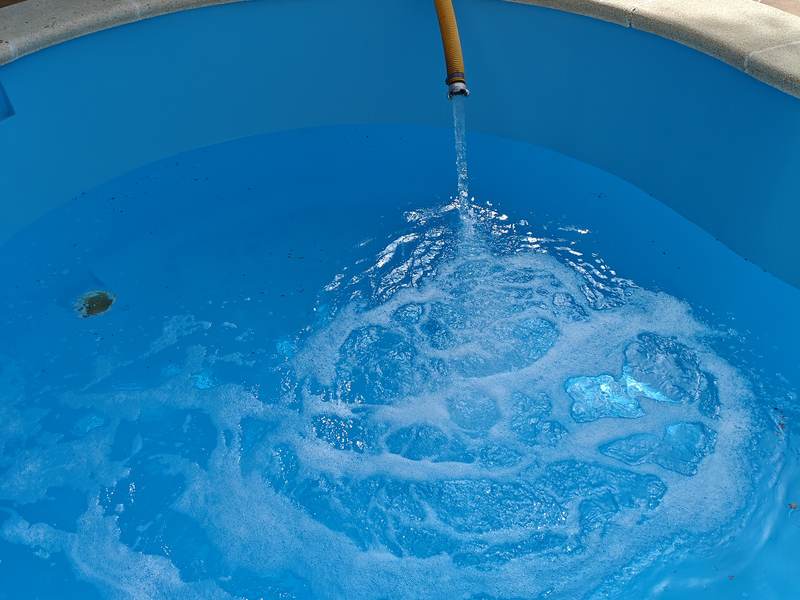 Piscina rodona omplint-se amb la mànega del camió cisterna